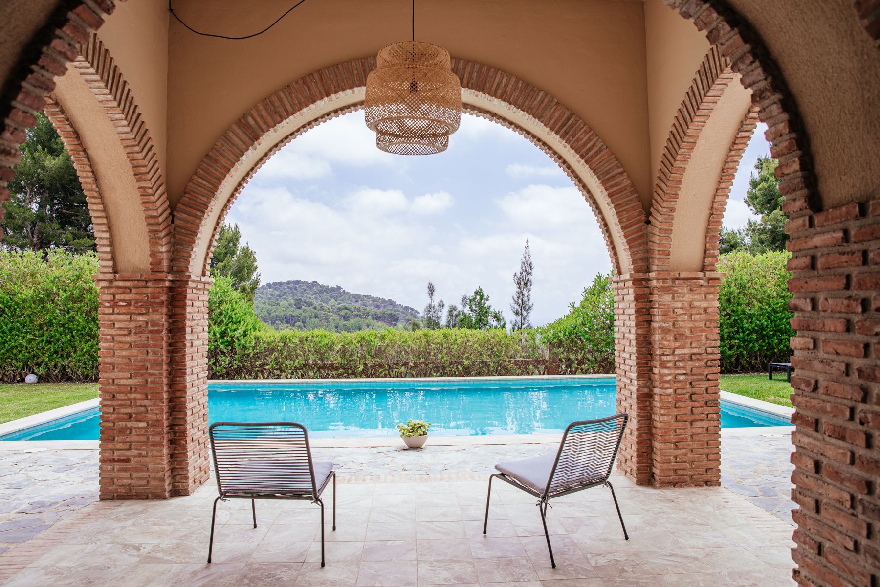 Brick archways framing the pool and Sierra Calderona mountains at Savi Coliving
